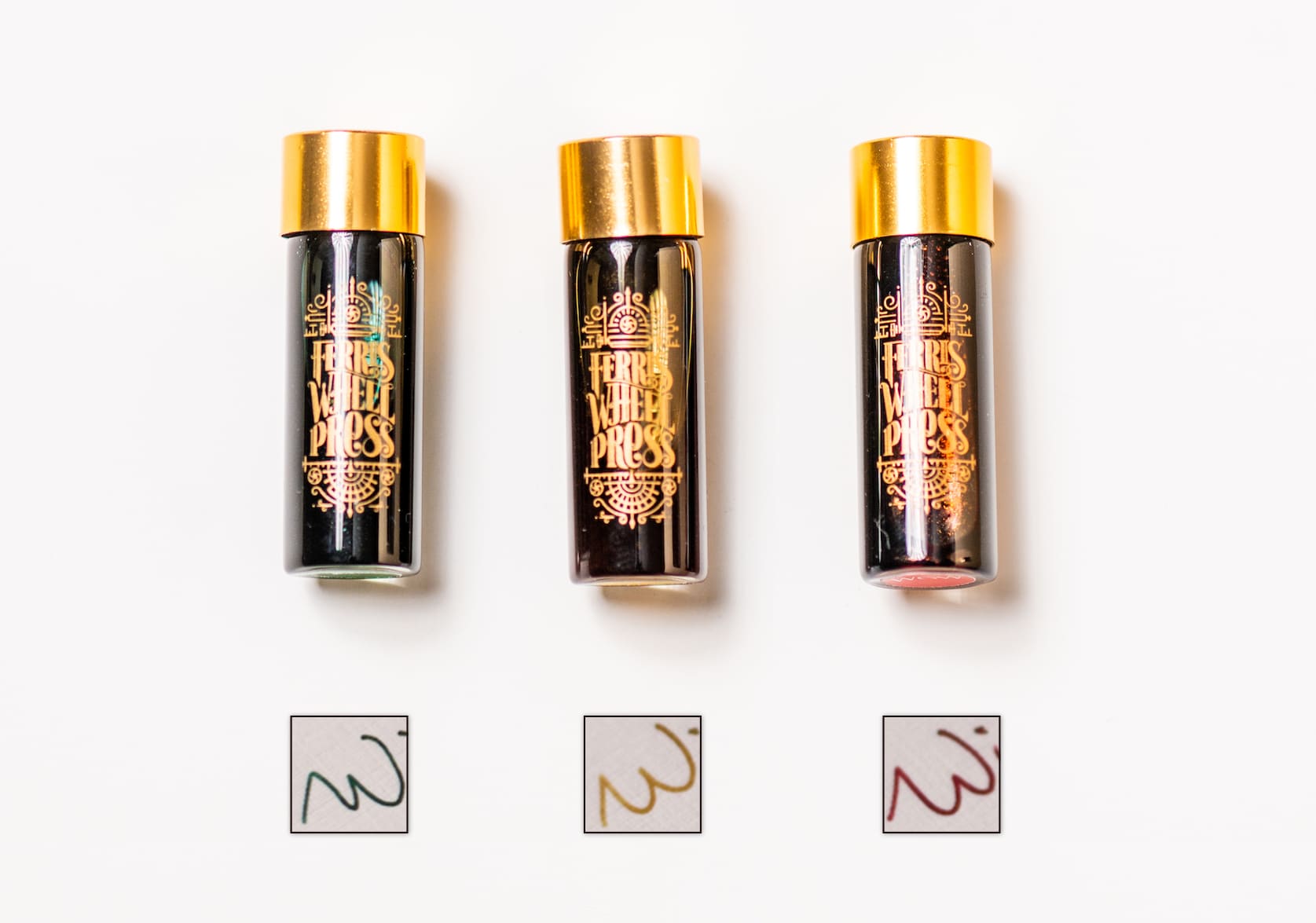 Three vials of ink centered against a white background. Below each vial is a square with "W" written inside it, in the three different colours of the vials: mistletoe, champagne, winterberry.