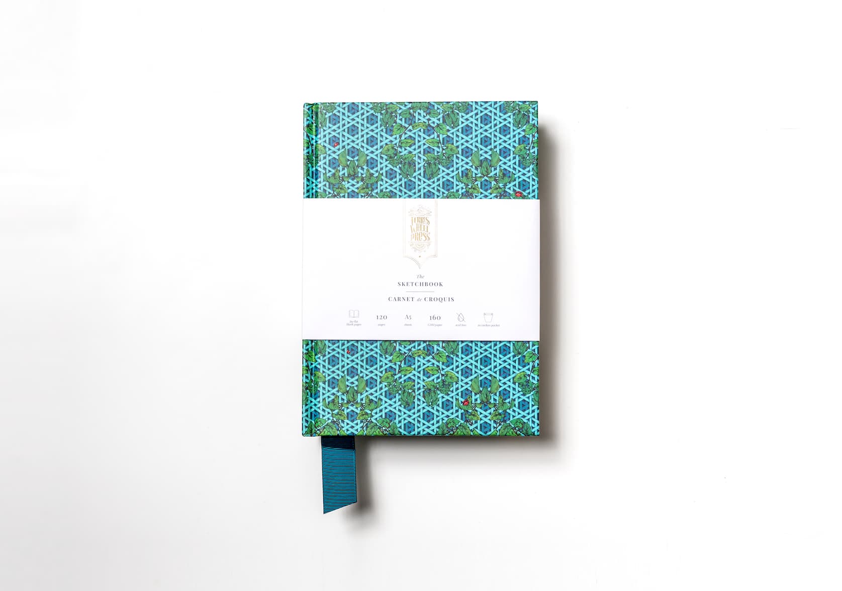 A teal sketchbook covered in paper with a hand-illustrated rattan pattern featuring a teal fabric ribbon sticking out of the bottom. Gold text on the notebook's packaging reads: Ferris Wheel Press logo. The Sketchbook. Carnet de Croquis.