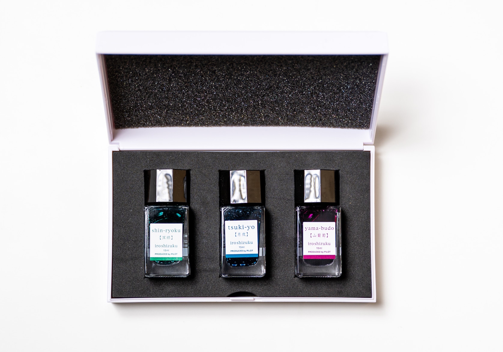 Three vials of ink displayed in a small box. Text on each bottle reads: shin-ryoku, tsuki-yo, yama-budo. iroshizuku. 15 ml. Produced by Pilot. Each bottle's label features the colour of the ink: green, blue, burgundy.