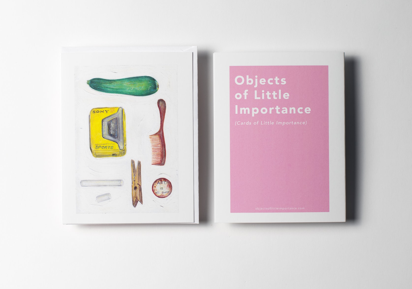 White greeting card featuring paintings of a zucchini, a yellow sony walkman, a brown comb, one and a half white chalk sticks, a clothspin, and a pin with text that reads: Art is all over. Back of the card is a pink rectangle with white text that reads: Objects of Little Importance (Cards of Little Importance).