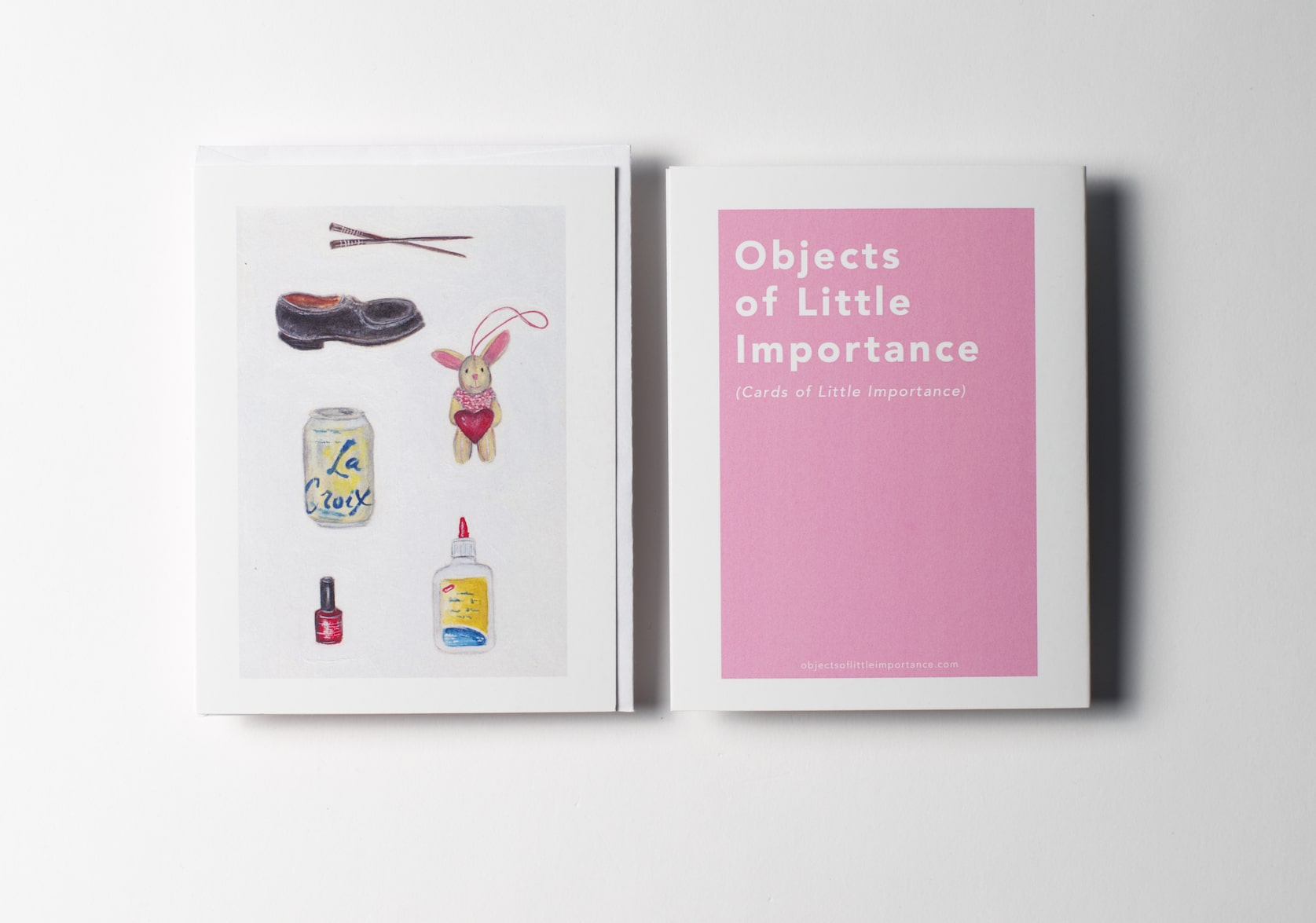 White greeting card featuring paintings of a pair of chopsticks, a black shoe, a tiny stuffed rabbit holding a red heart, a can of La Croix, a bottle of red nail polish, and bottle of white glue. Back of the card is a pink rectangle with white text that reads: Objects of Little Importance (Cards of Little Importance).