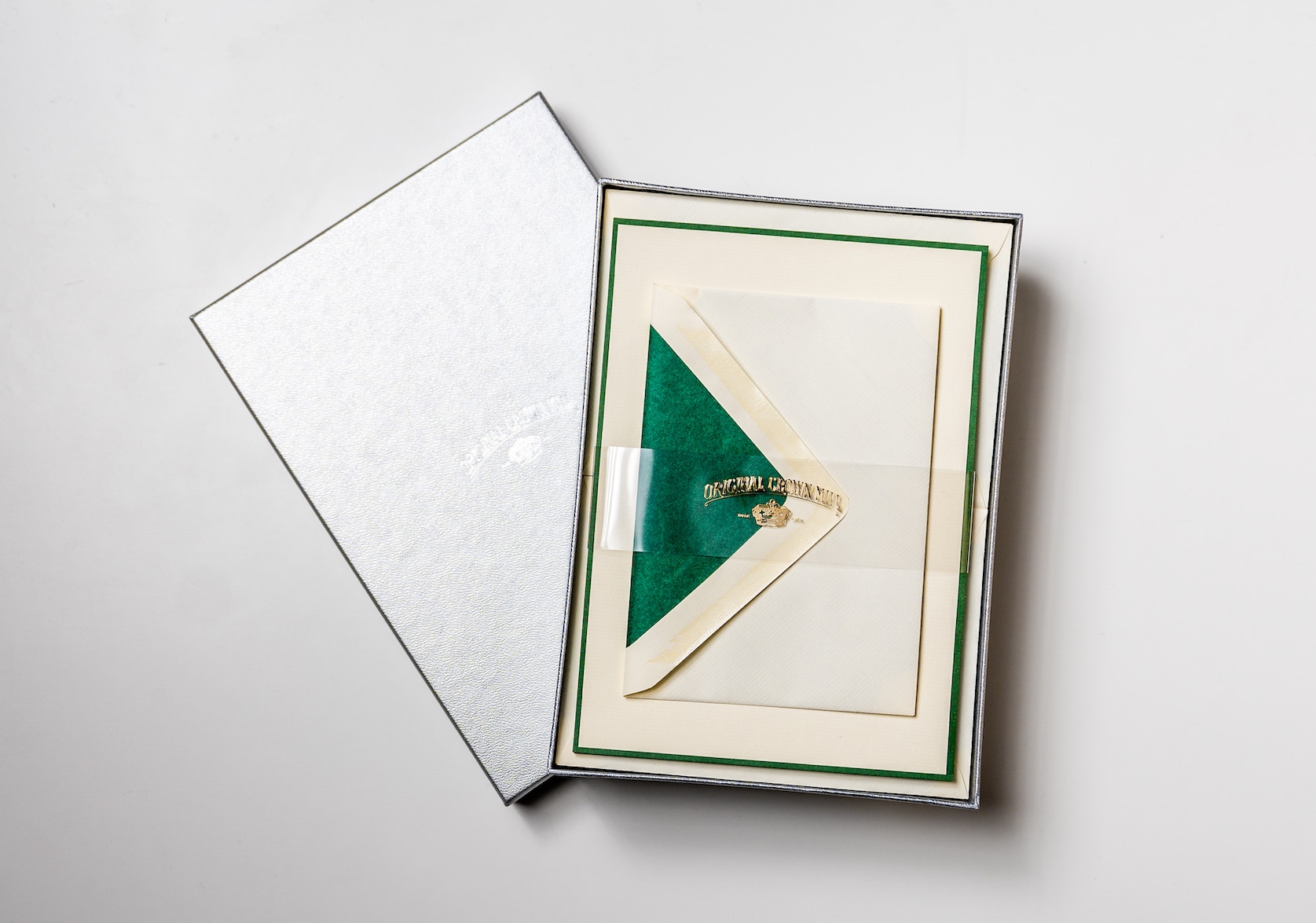 Open silver box set of cream stationary with a dark green edge. Clear packaging across the box with gold text that reads: Original Crown Mill. Below there is a small gold illustration of a crown.