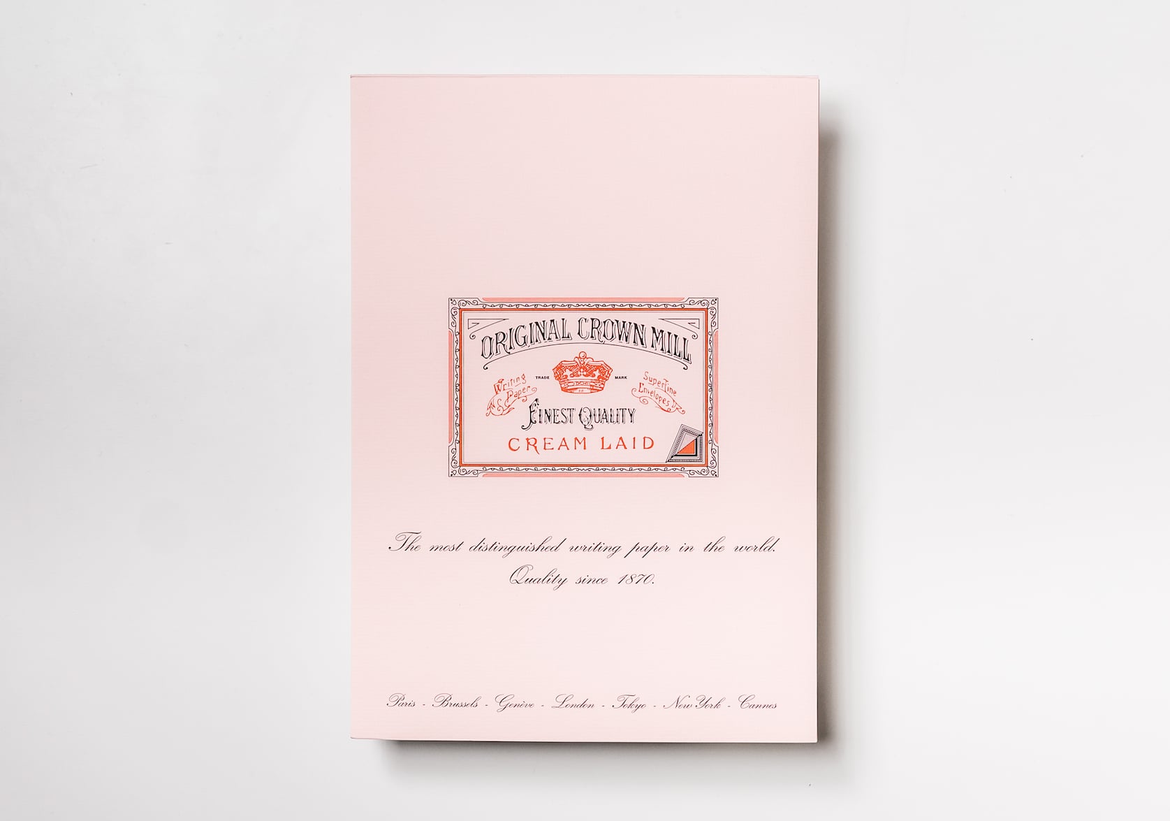 Pink Notepad sized A4. In the centre there is a stamped red & black logo with a red crown. Text that reads: Original Crown Mill. Finest Quality. Cream Laid. Below cursive text reads: The most distinguishable writing paper in the world. Quality since 1870.