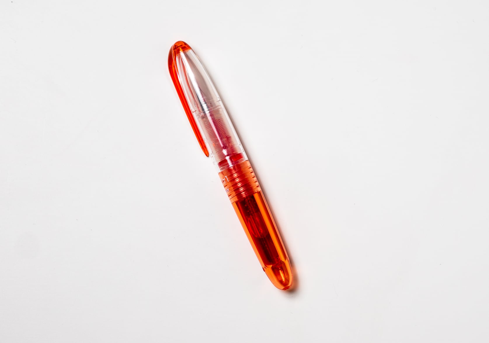 Small red fountain pen with a clear cap and red clip
