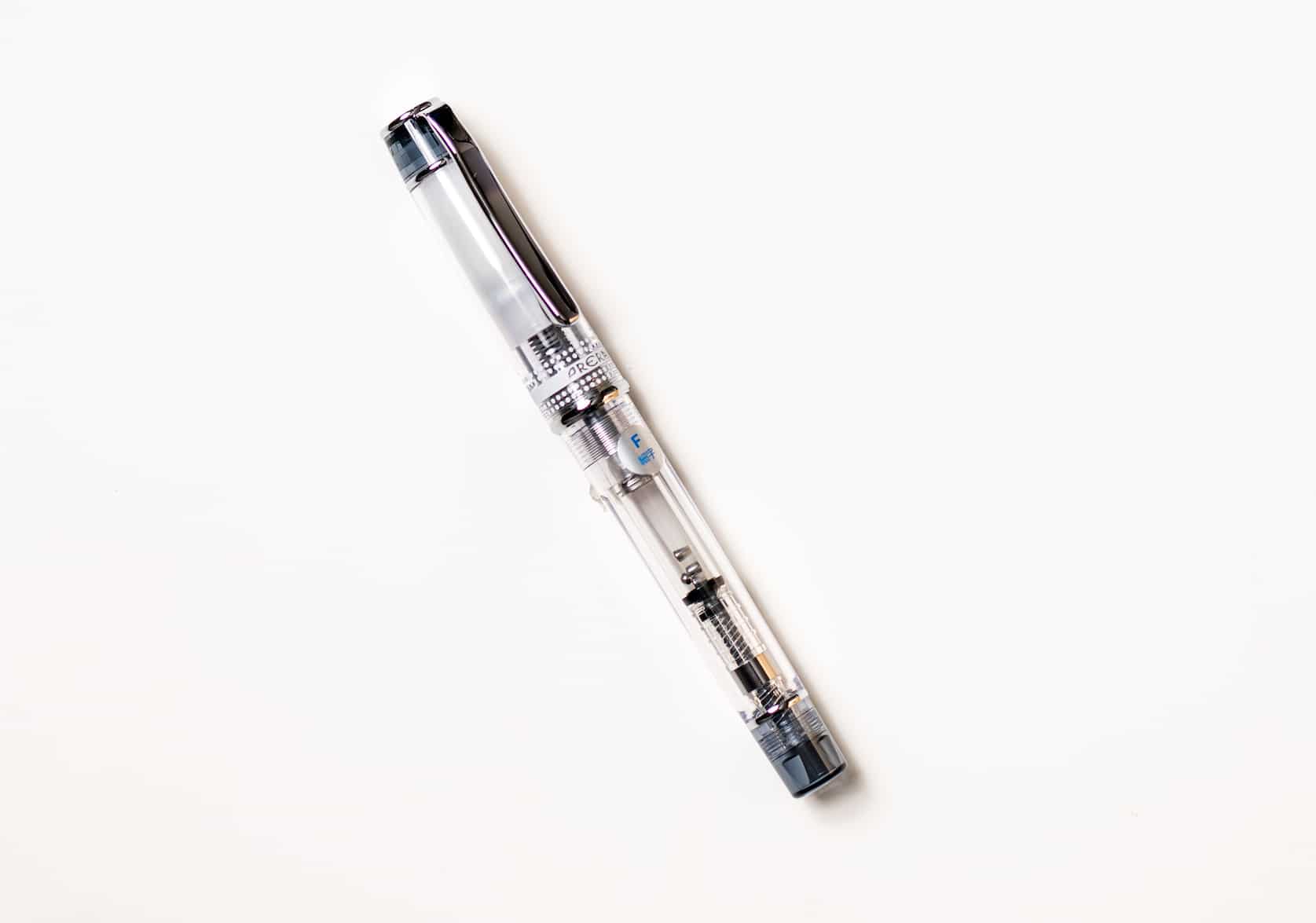 Transparent fountain pen with silver pen clip. Tinted black details on the top of the pen cap and bottom of the barrel
