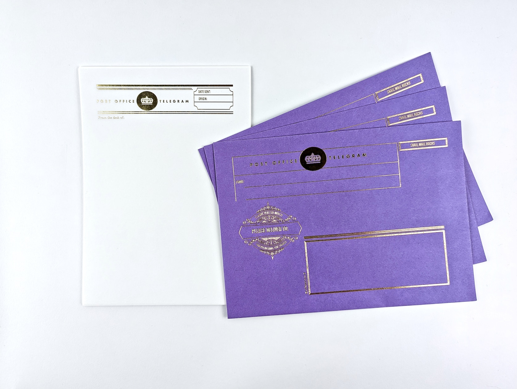 Three purple gold foiled envelopes featuring a gold crown, fake postage and text reads: Post Office Telegram. Please Deliver To. Includes white gold foiled letter writing paper in a retro telegram design.