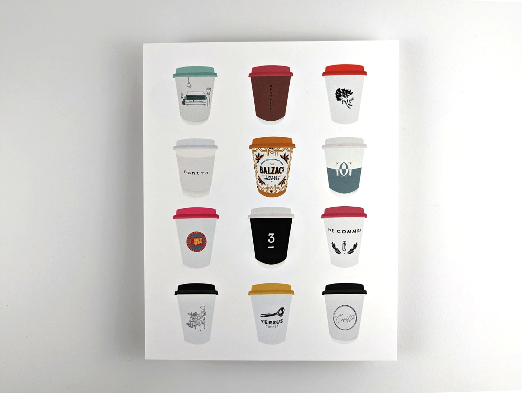 Print featuring illustrations of twelve coffee to-go cups from Toronto cafés against a white background. The twelve coffee cups are arranged in 4 rows with 3 cups in each row.