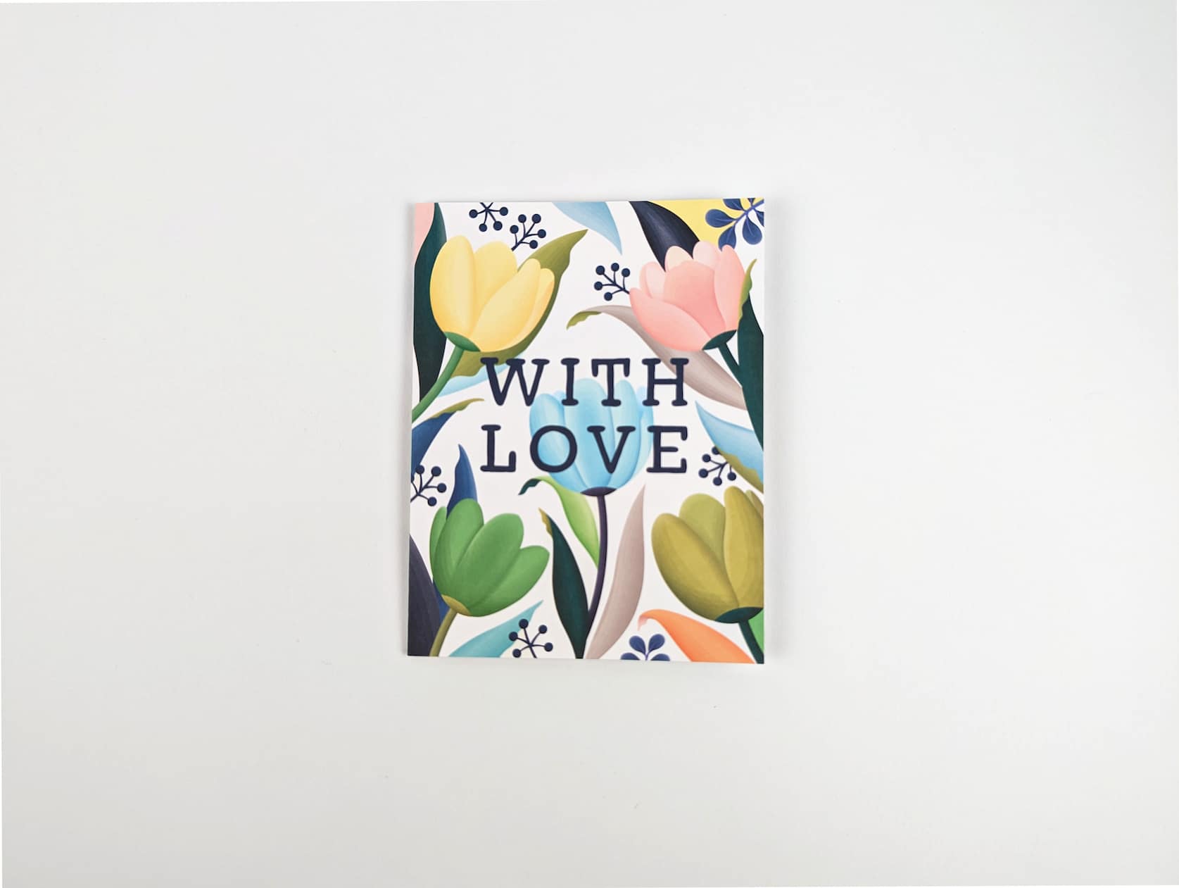 White horizontal card with blue text in the centre that reads: WITH LOVE. A variety of pastel blue, yellow, green and pink tulips, blue, green and orange leaves, and blue sprigs featured behind the text.