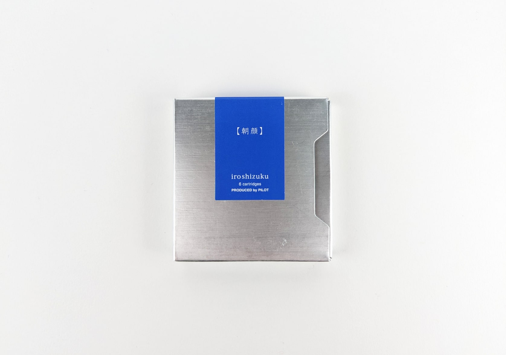 Silver sliding box. Rectangular royal blue sticker with white text that reads: asa-gao. iroshizuku. 6 cartridges. Produced by Pilot.