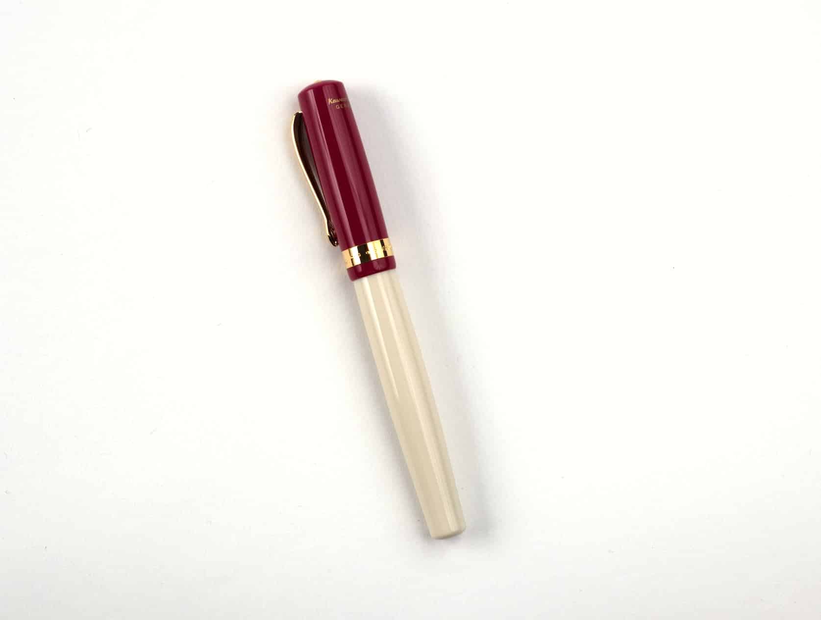 A cream fountain pen with a bordeaux red cap and golden accents.