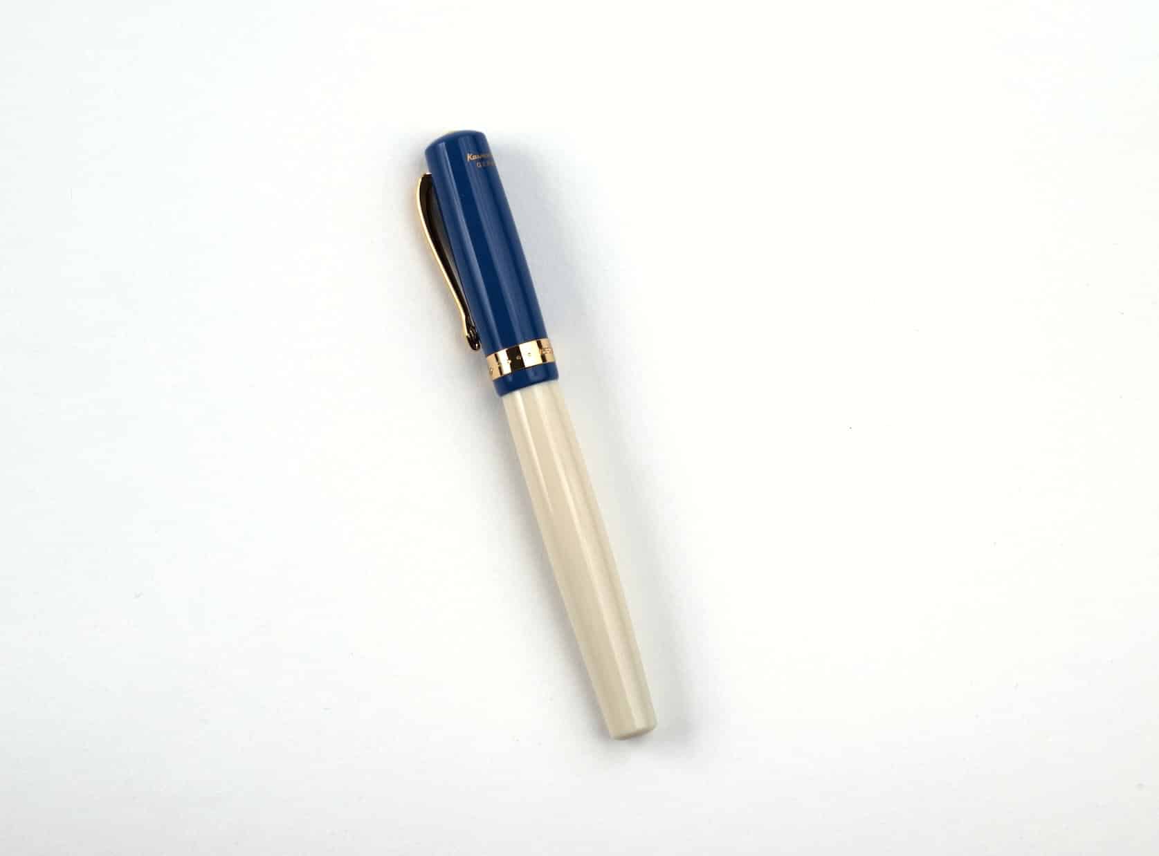 A cream fountain pen with a blue cap and golden accents.