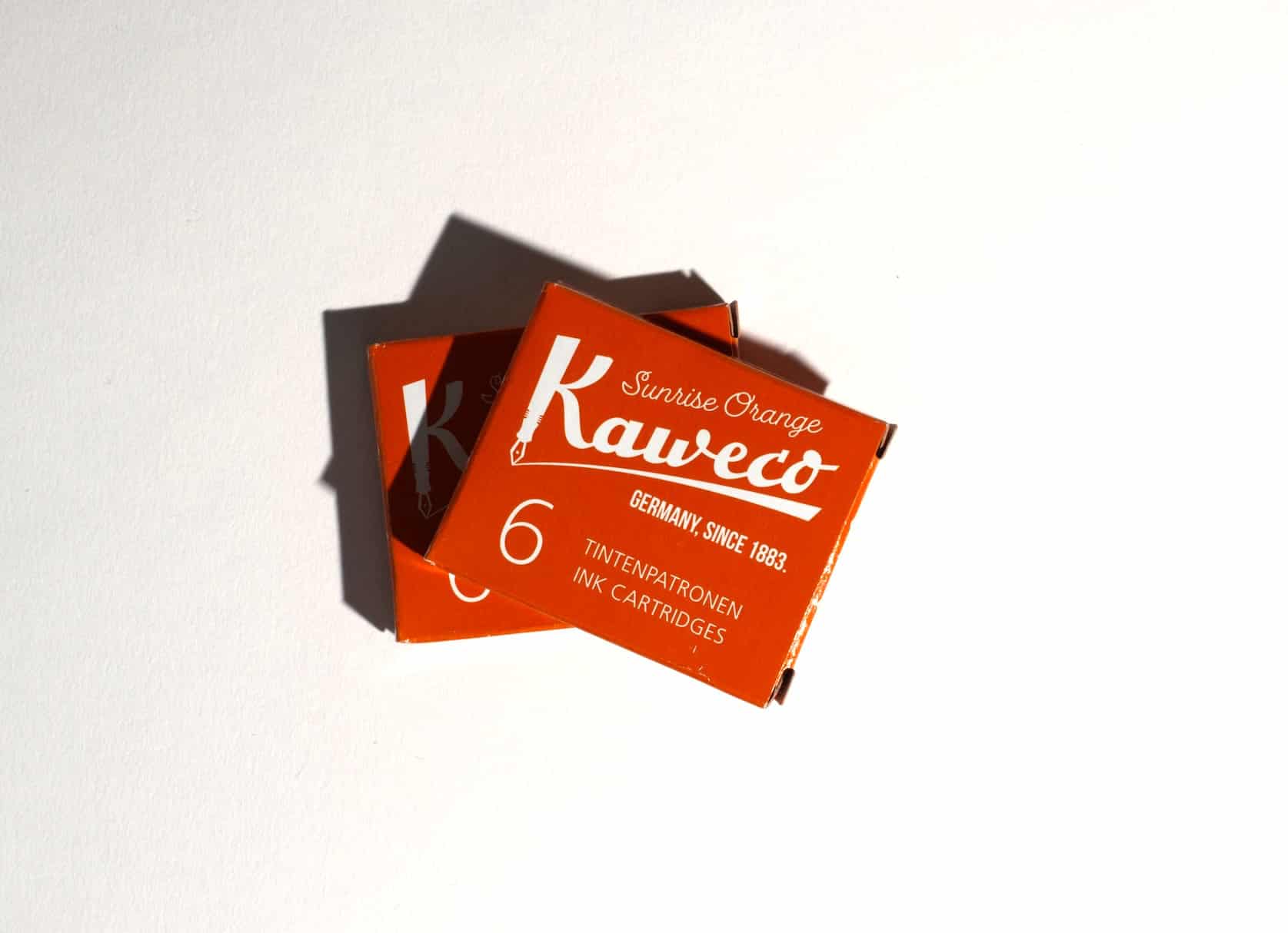 Two boxes of ink cartridges lie on a white surface. Text on packaging reads: Kaweco. Sunrise Orange. Germany, since 1883. 6 Tintenpatronen. Ink Cartridges.