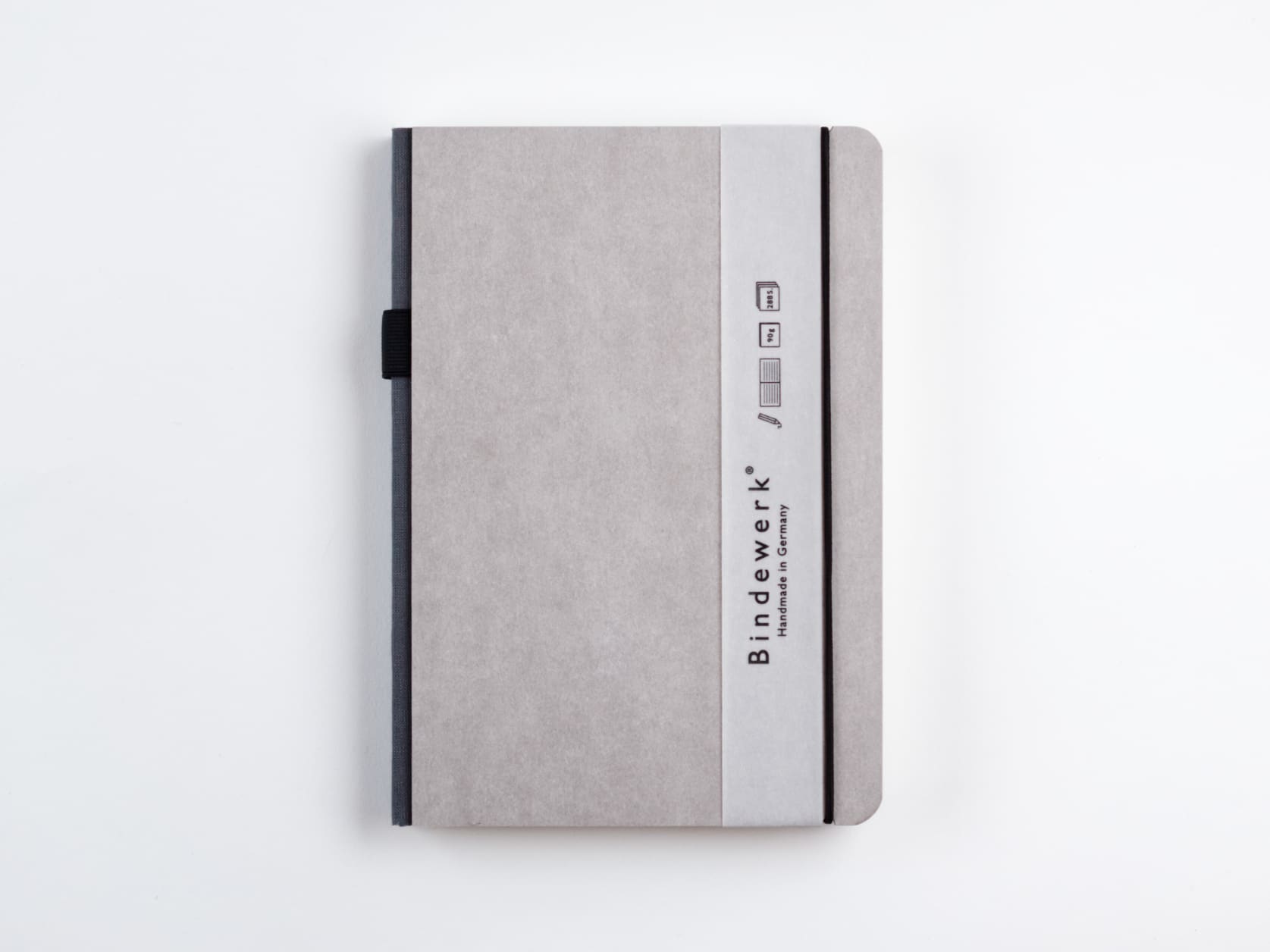 Grey notebook with a dark grey spine, a black elastic and a slim sleeve with the Bindewerk logo and the words Handmade in Germany.