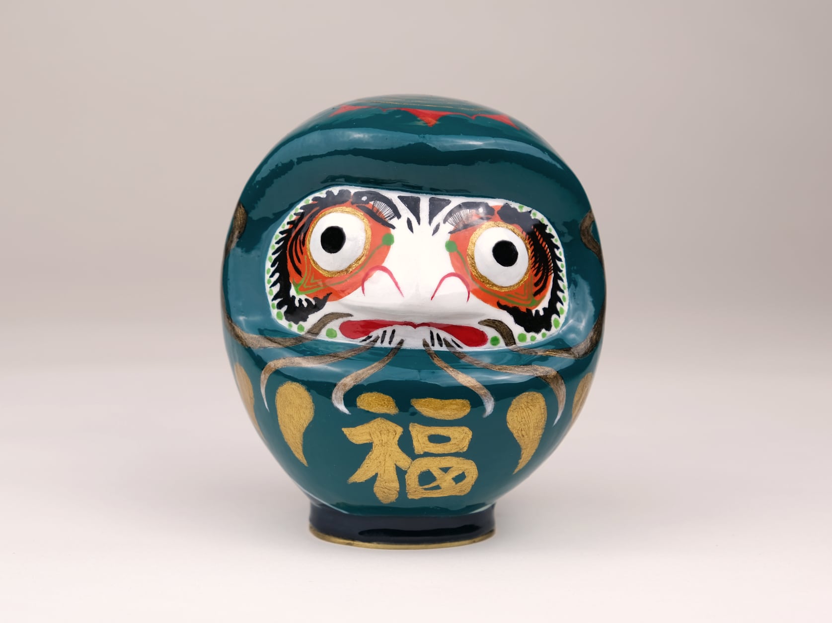 a sculpture of a blue Daruma with many embellishments